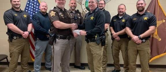 Group of sheriff's with donation, shaking hands.
